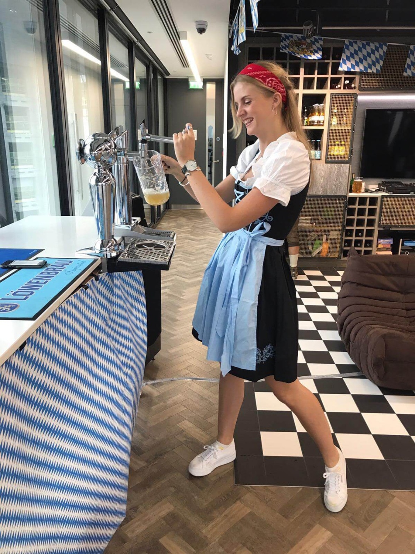 Lady smiling and pouring beer from a tap in a traditional German dress